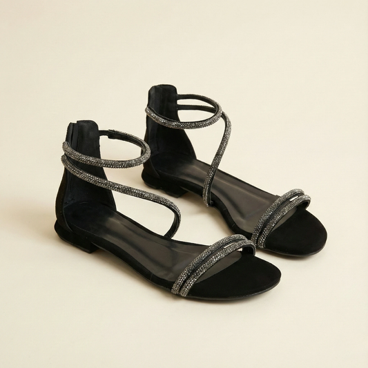 Black sandals with silver straps on a beige background